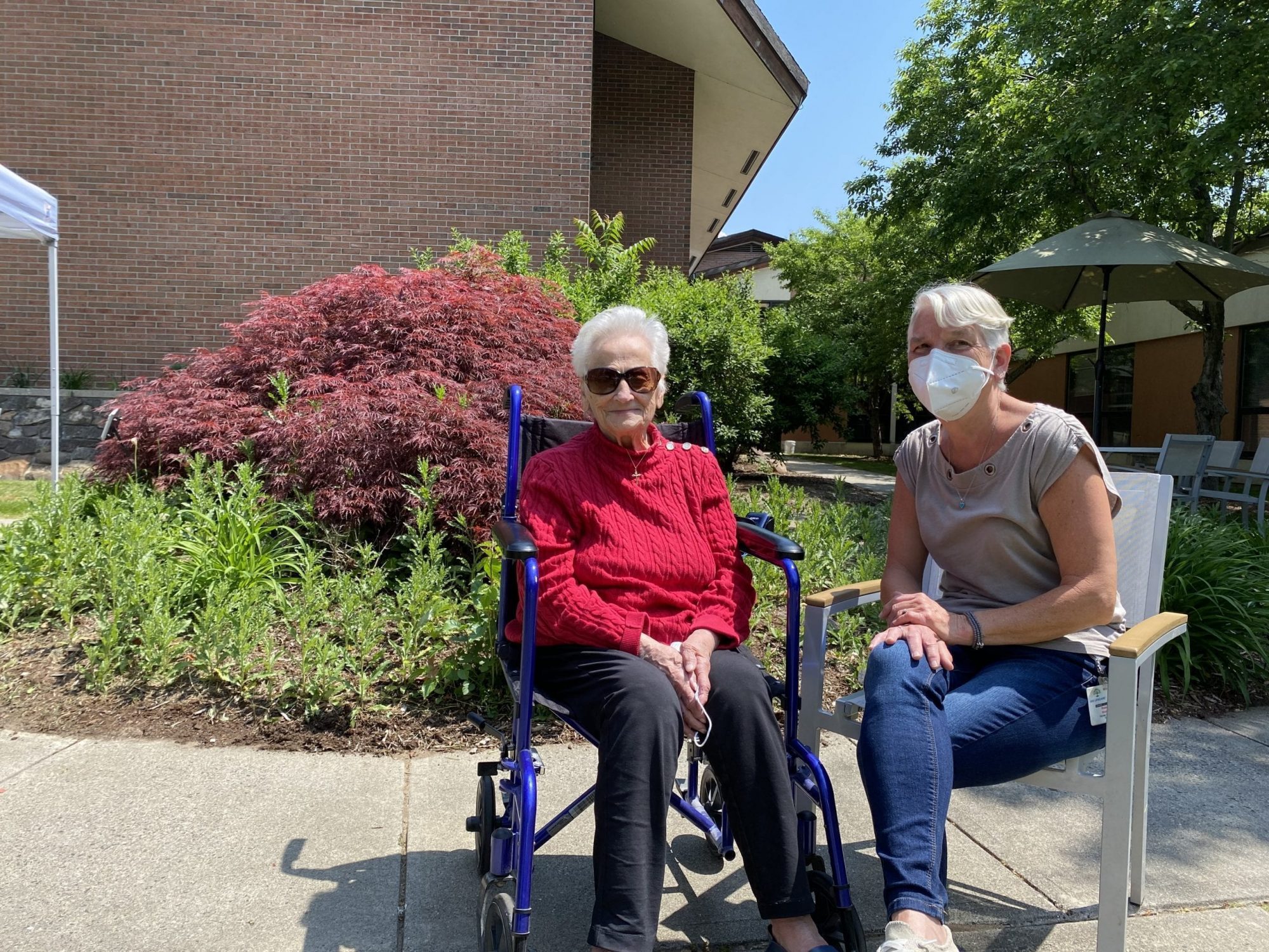 A resident and a home health aid relax outdoors.