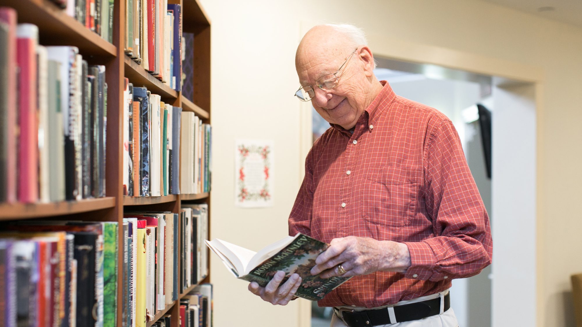 A resident choosing a book from the library at Ruth's House