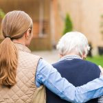 A caregiver walking with an older woman.