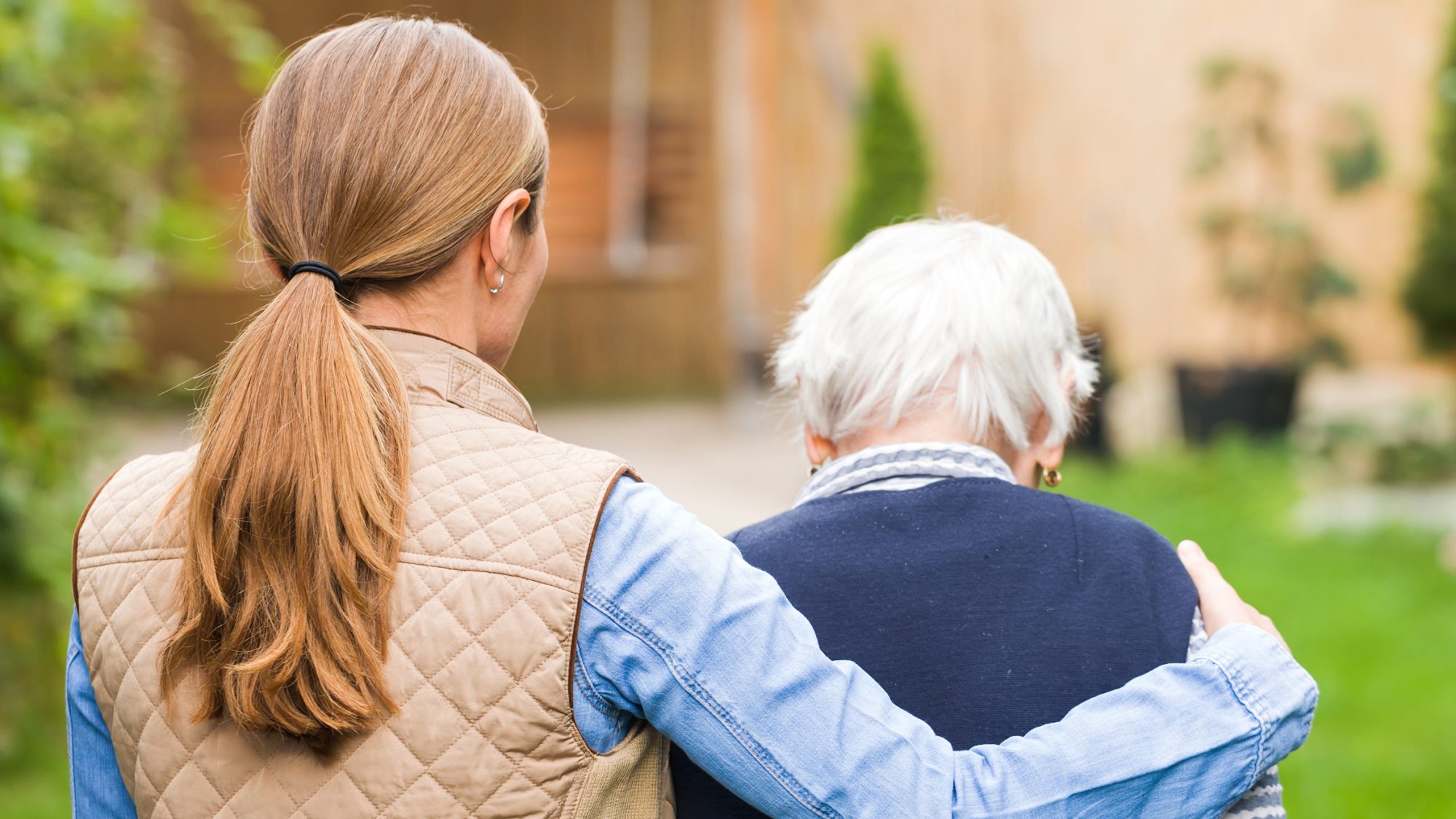 A caregiver walking with an older woman.