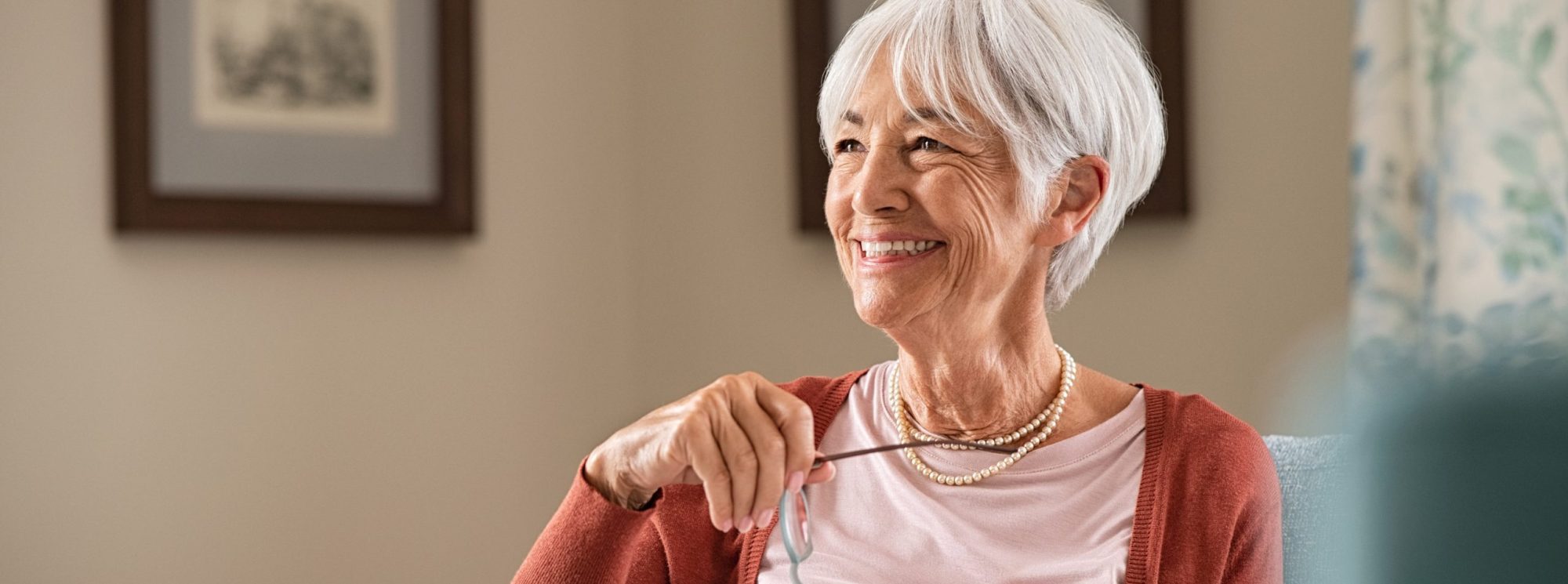 An older woman happily looking to her right with an open book in her lap.