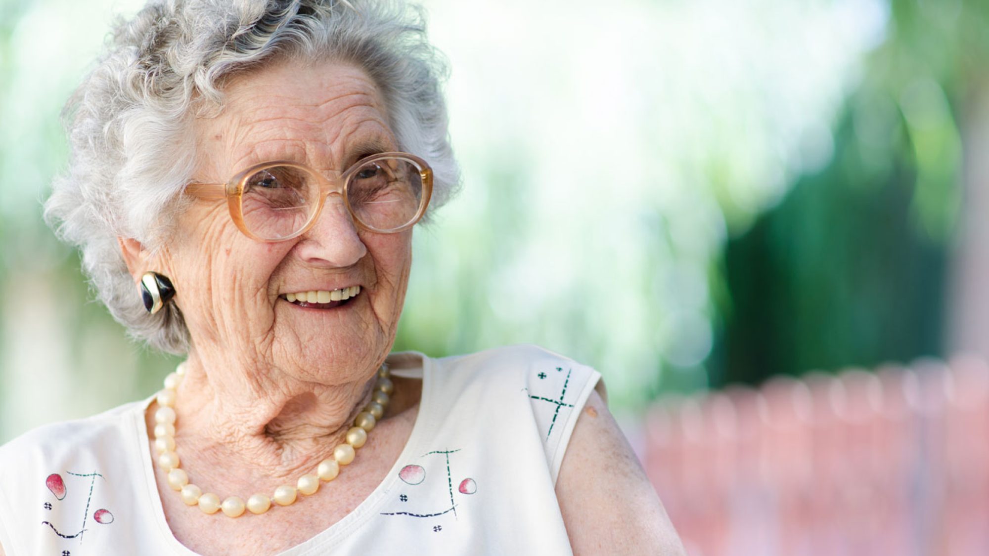 An older woman with short grey hair and brown glasses laughing and looking to her left