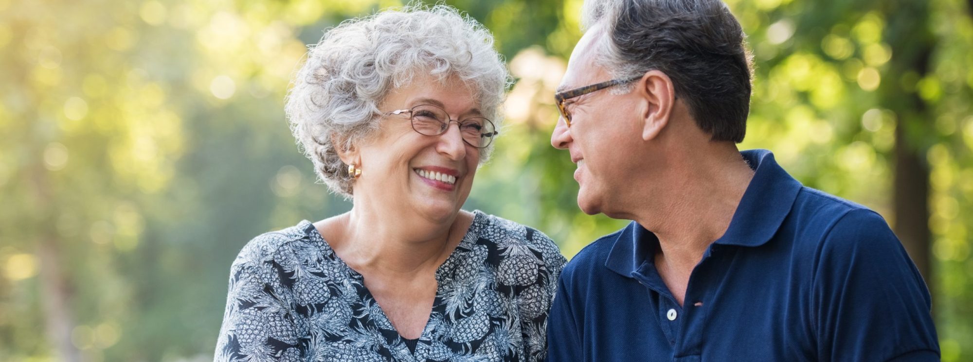 An older couple happily smiling at each other outside