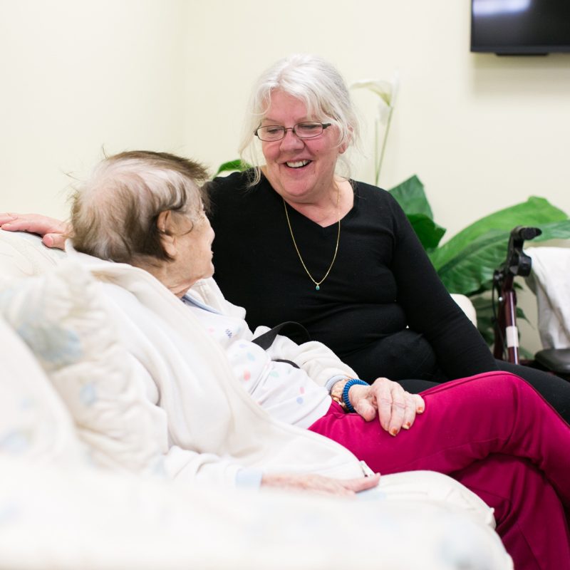 An employee of JGS sitting with a resident.