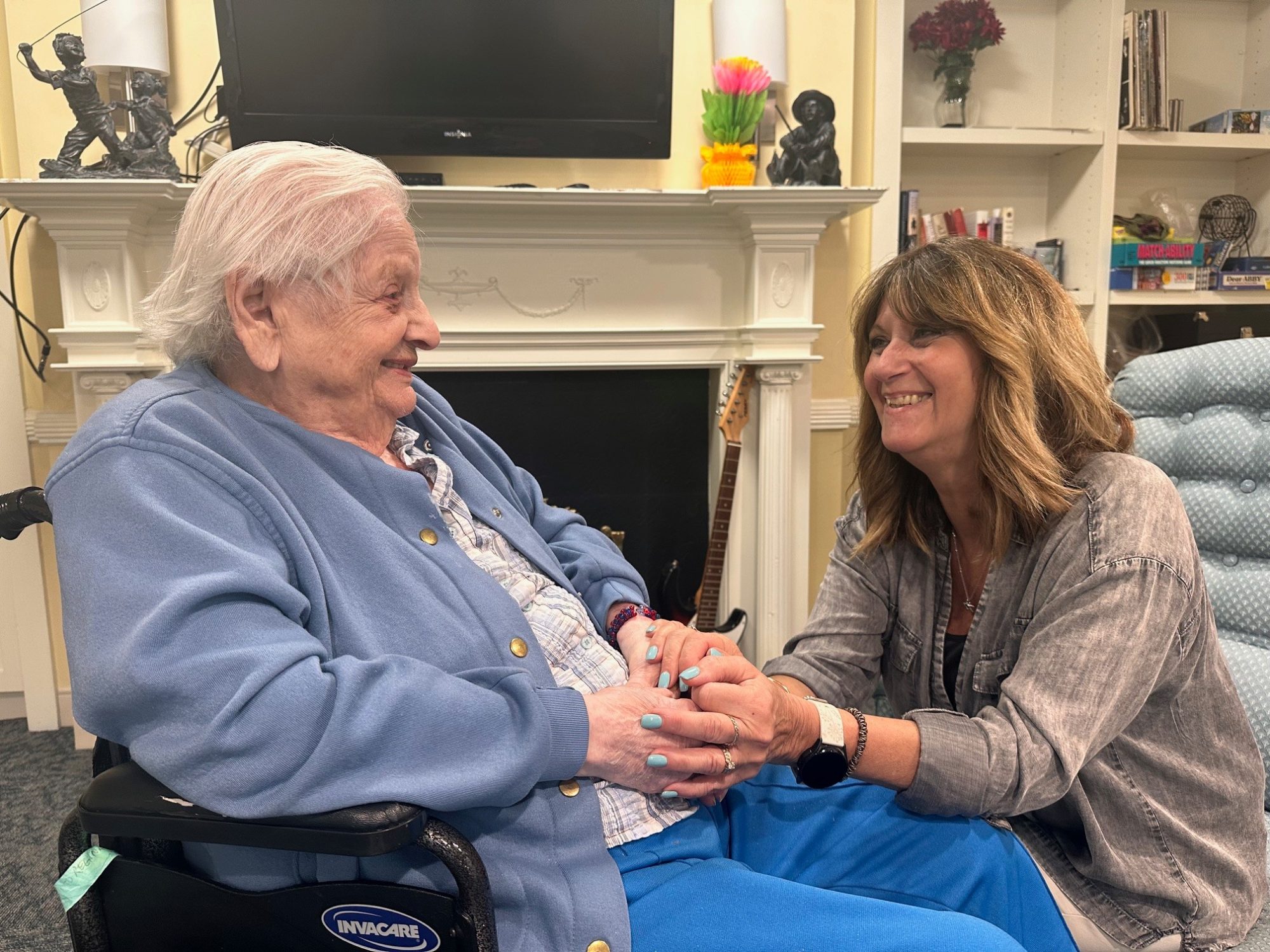 Cheryl lovingly holding the hands of a resident